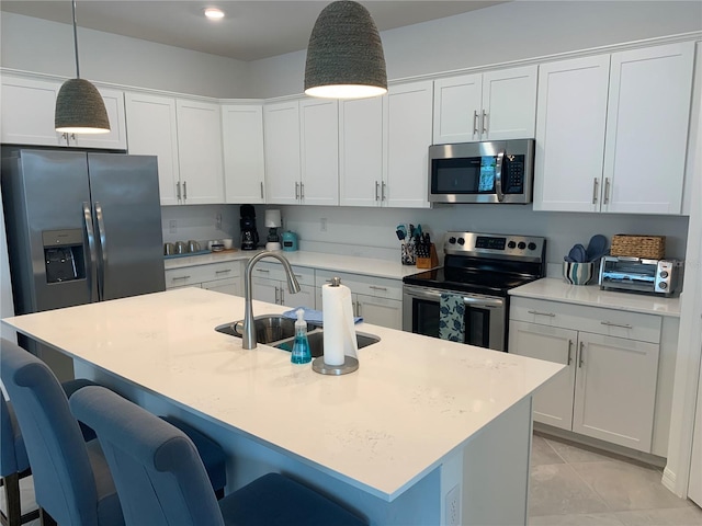 kitchen featuring appliances with stainless steel finishes, a breakfast bar area, pendant lighting, and a center island with sink