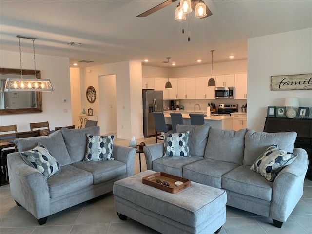 tiled living room with ceiling fan and sink