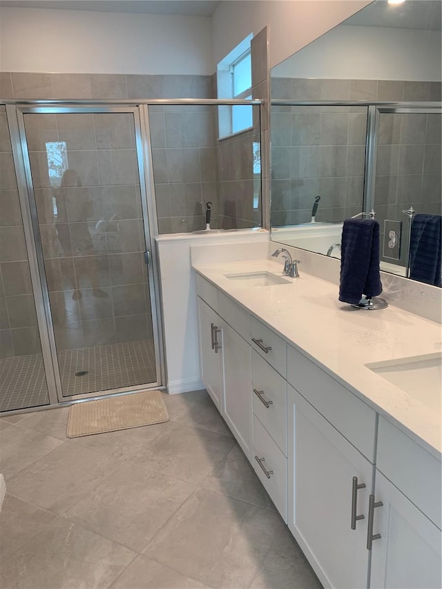 bathroom with tile flooring, a shower with door, and dual bowl vanity