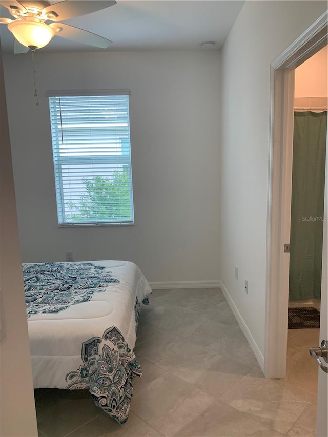 tiled bedroom featuring ceiling fan and a walk in closet