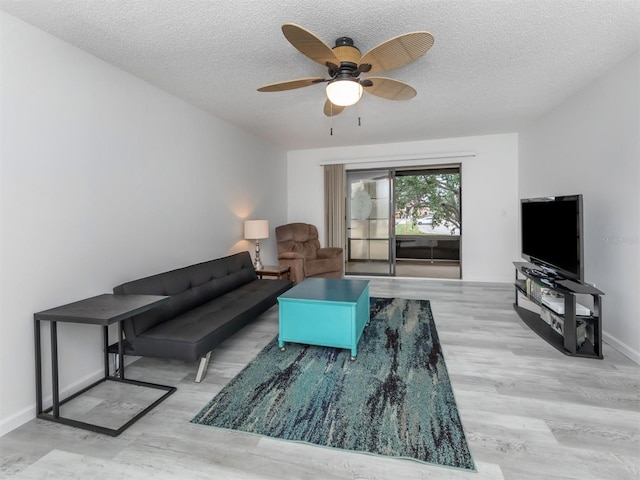 living room featuring a textured ceiling, ceiling fan, and light wood-type flooring