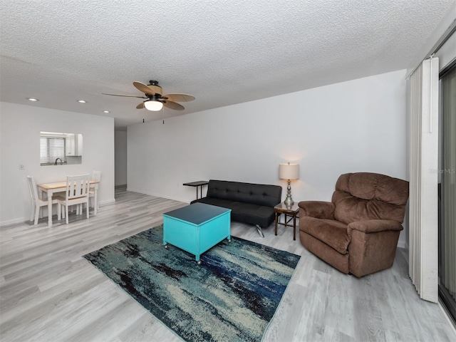 living room featuring a textured ceiling, light hardwood / wood-style floors, and ceiling fan