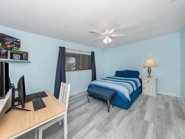 bedroom with ceiling fan, light hardwood / wood-style flooring, and a textured ceiling