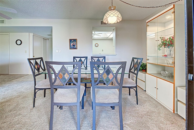 carpeted dining space featuring a textured ceiling