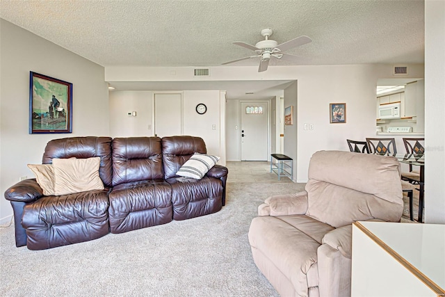 carpeted living room with ceiling fan and a textured ceiling