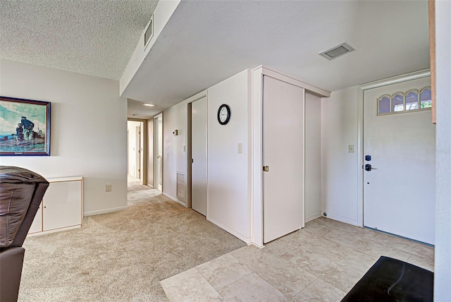 carpeted foyer entrance featuring a textured ceiling