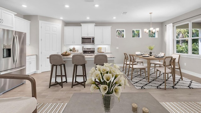 kitchen with decorative light fixtures, appliances with stainless steel finishes, and white cabinetry