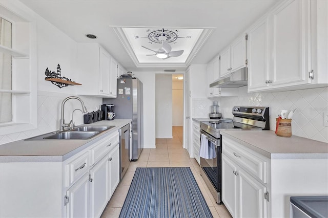 kitchen with sink, stainless steel appliances, white cabinets, a tray ceiling, and light tile patterned flooring