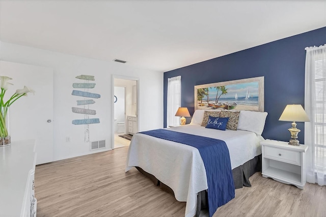 bedroom featuring ensuite bathroom and light hardwood / wood-style floors