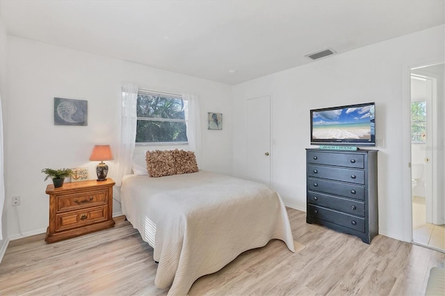 bedroom featuring light wood-type flooring and ensuite bath