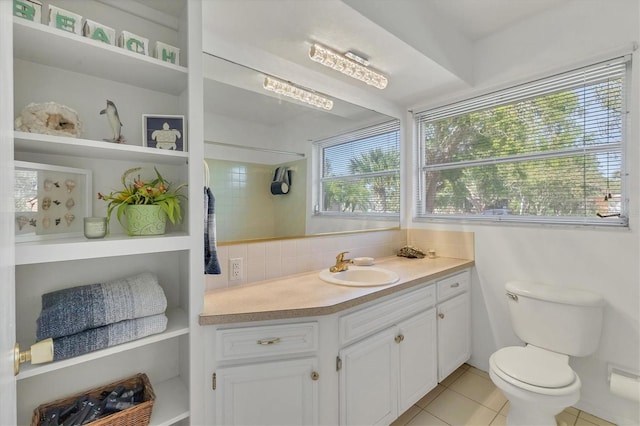 bathroom featuring tile patterned flooring, vanity, a healthy amount of sunlight, and backsplash