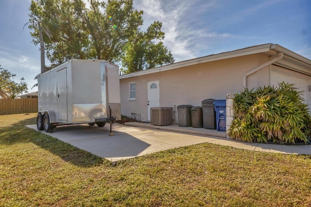 rear view of house with central air condition unit and a lawn