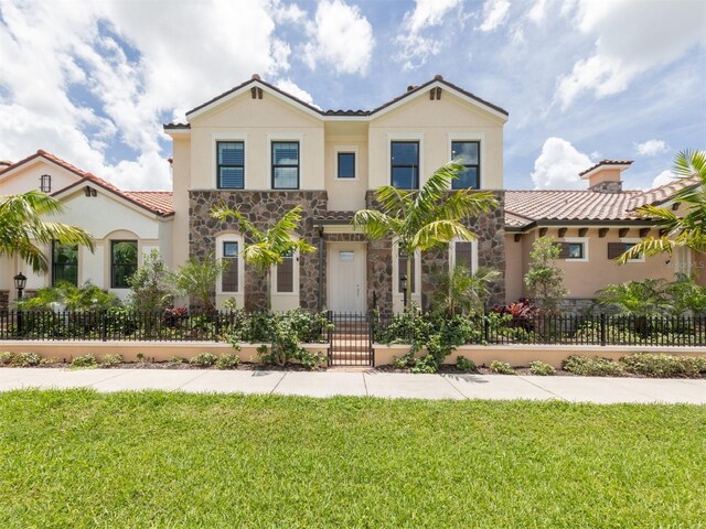 922 E Venice Ave, Venice, FL 34285 - mediterranean / spanish-style house with stucco siding, a fenced front yard, a front yard, and stone siding