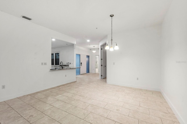 unfurnished living room featuring a notable chandelier, sink, and light tile patterned floors