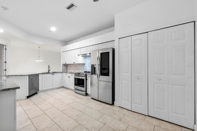 kitchen with hanging light fixtures, appliances with stainless steel finishes, light tile patterned floors, and backsplash