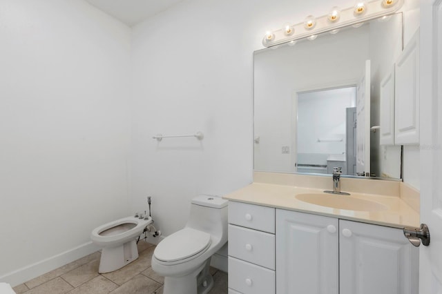 bathroom with tile patterned flooring, toilet, a bidet, and vanity