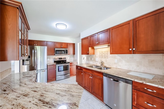 kitchen with light stone countertops, tasteful backsplash, sink, and stainless steel appliances