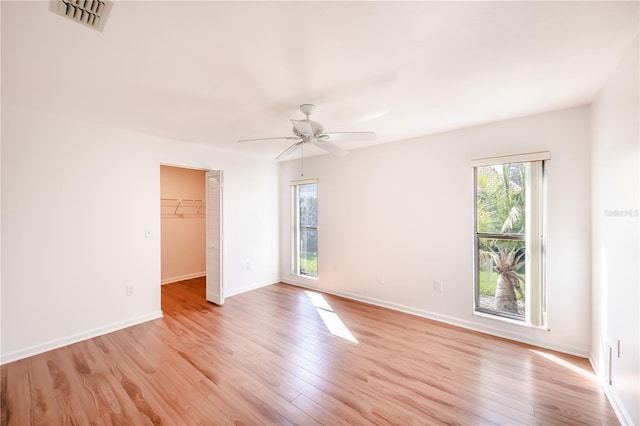 interior space featuring a closet, a walk in closet, ceiling fan, and light wood-type flooring