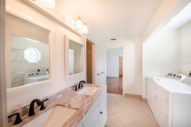 bathroom with dual vanity, tile floors, and washer and dryer