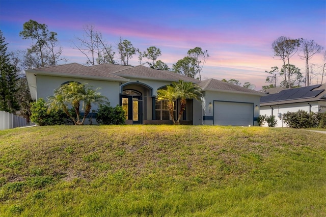 ranch-style home featuring solar panels, a yard, and a garage