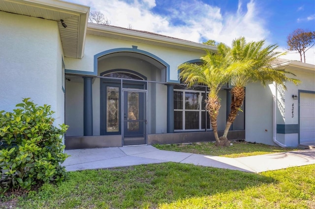 entrance to property with french doors and a lawn