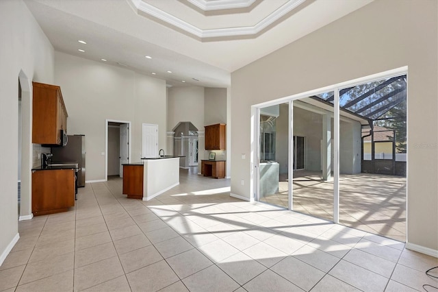 spare room featuring light tile floors, a raised ceiling, and a high ceiling