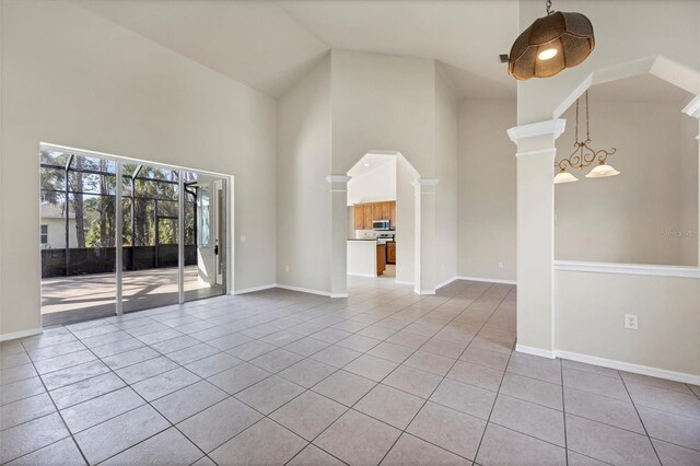 unfurnished living room with light tile floors, high vaulted ceiling, and an inviting chandelier