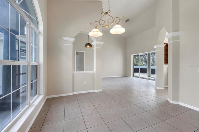 empty room with a chandelier, light tile floors, and high vaulted ceiling