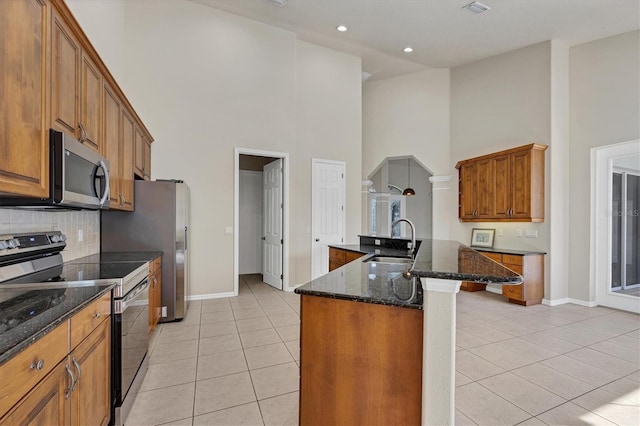 kitchen with range with electric stovetop, a towering ceiling, sink, and light tile flooring