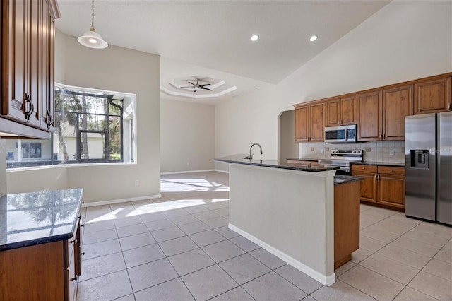 kitchen featuring a kitchen island with sink, pendant lighting, ceiling fan, appliances with stainless steel finishes, and tasteful backsplash