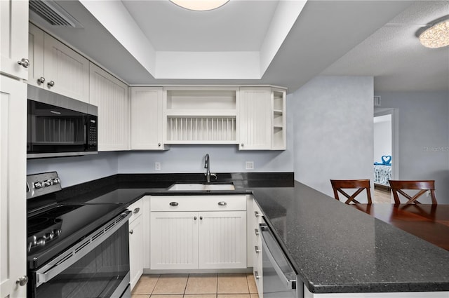 kitchen featuring a raised ceiling, appliances with stainless steel finishes, and white cabinetry