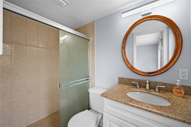 bathroom with toilet, vanity, and a shower with shower door