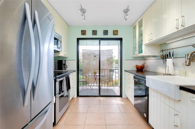 kitchen featuring tasteful backsplash, stainless steel appliances, light tile floors, and rail lighting