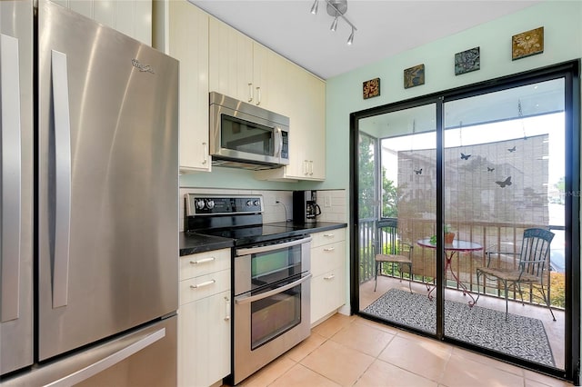 kitchen with light tile floors, appliances with stainless steel finishes, rail lighting, and backsplash