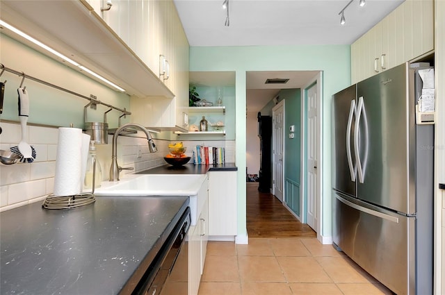 kitchen featuring light tile floors, rail lighting, stainless steel fridge, backsplash, and sink