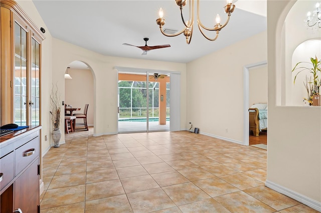 tiled spare room featuring ceiling fan with notable chandelier