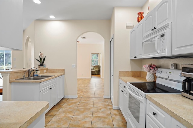 kitchen featuring white cabinets, light tile flooring, white appliances, and sink