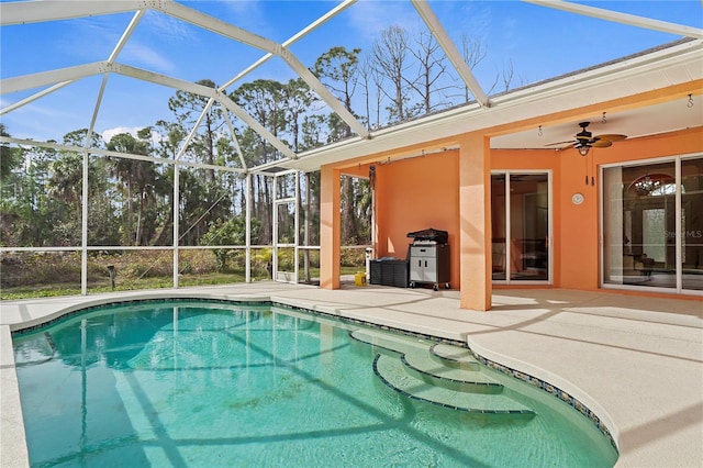 view of pool with a patio area, ceiling fan, and glass enclosure