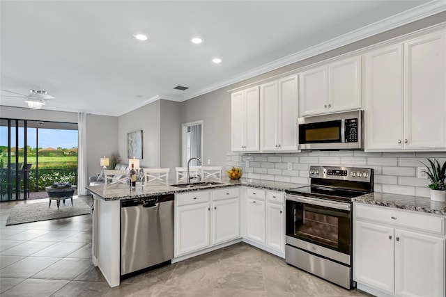 kitchen with white cabinets, sink, kitchen peninsula, appliances with stainless steel finishes, and crown molding