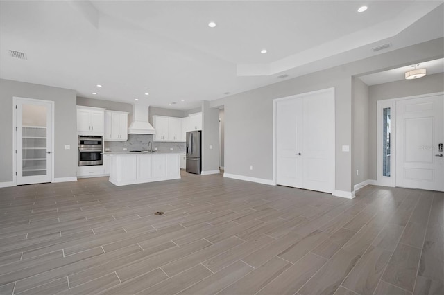 unfurnished living room with sink and light hardwood / wood-style floors