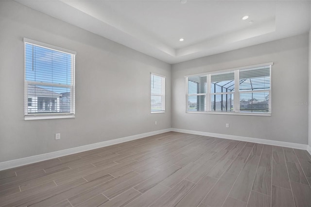 unfurnished room with hardwood / wood-style floors and a raised ceiling