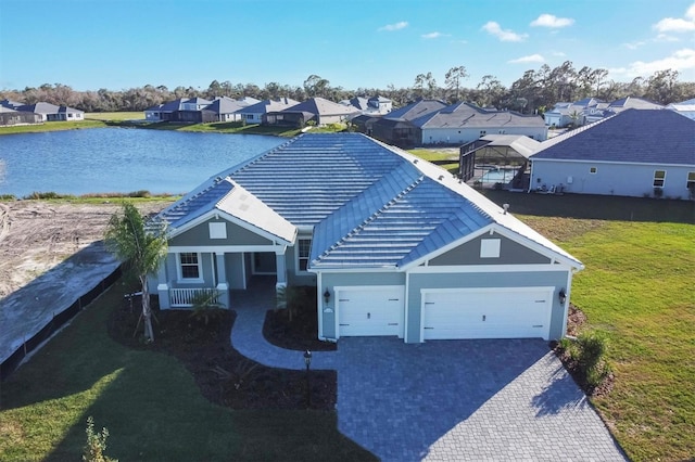 view of front of house featuring a water view, covered porch, a front yard, and a garage