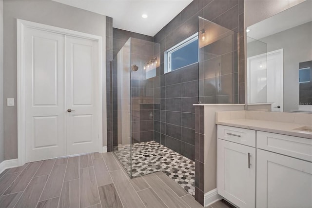 bathroom with a tile shower and vanity