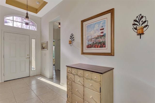 foyer entrance featuring light tile floors, a raised ceiling, and a towering ceiling