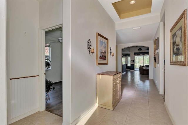 hall with a tray ceiling and light wood-type flooring