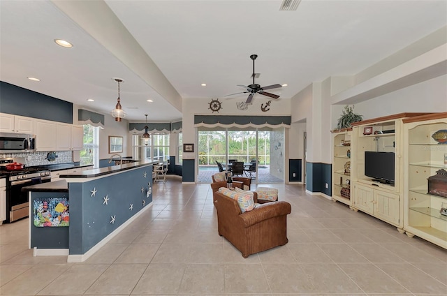 living room featuring a healthy amount of sunlight, ceiling fan, light tile floors, and sink