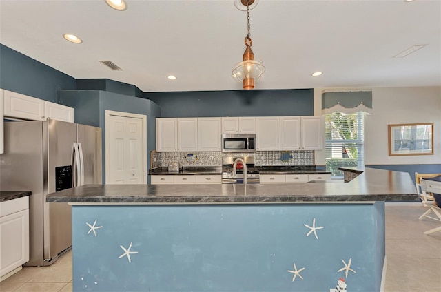 kitchen with light tile floors, a kitchen island with sink, appliances with stainless steel finishes, and white cabinetry