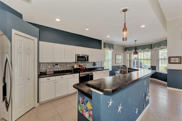 kitchen featuring white cabinets, decorative light fixtures, stainless steel appliances, and a kitchen island with sink