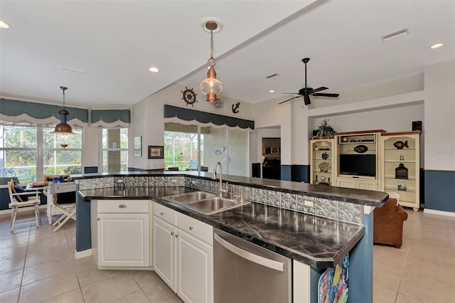 kitchen featuring an island with sink, pendant lighting, sink, stainless steel dishwasher, and white cabinetry