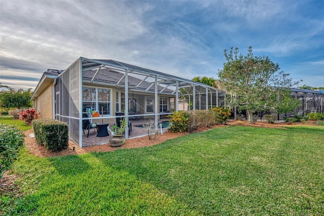 rear view of property with a lanai, a yard, and a patio area